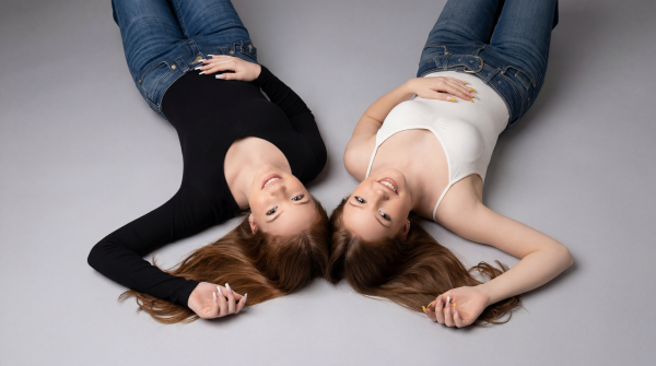 Emilia and Letizia laying on the floor, looking into the camera and smiling