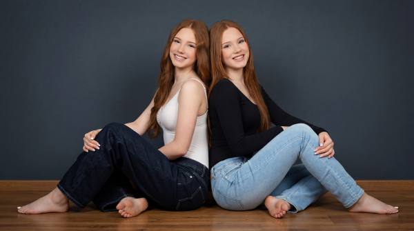 Emilia And Letizia sitting on a Wooden floor